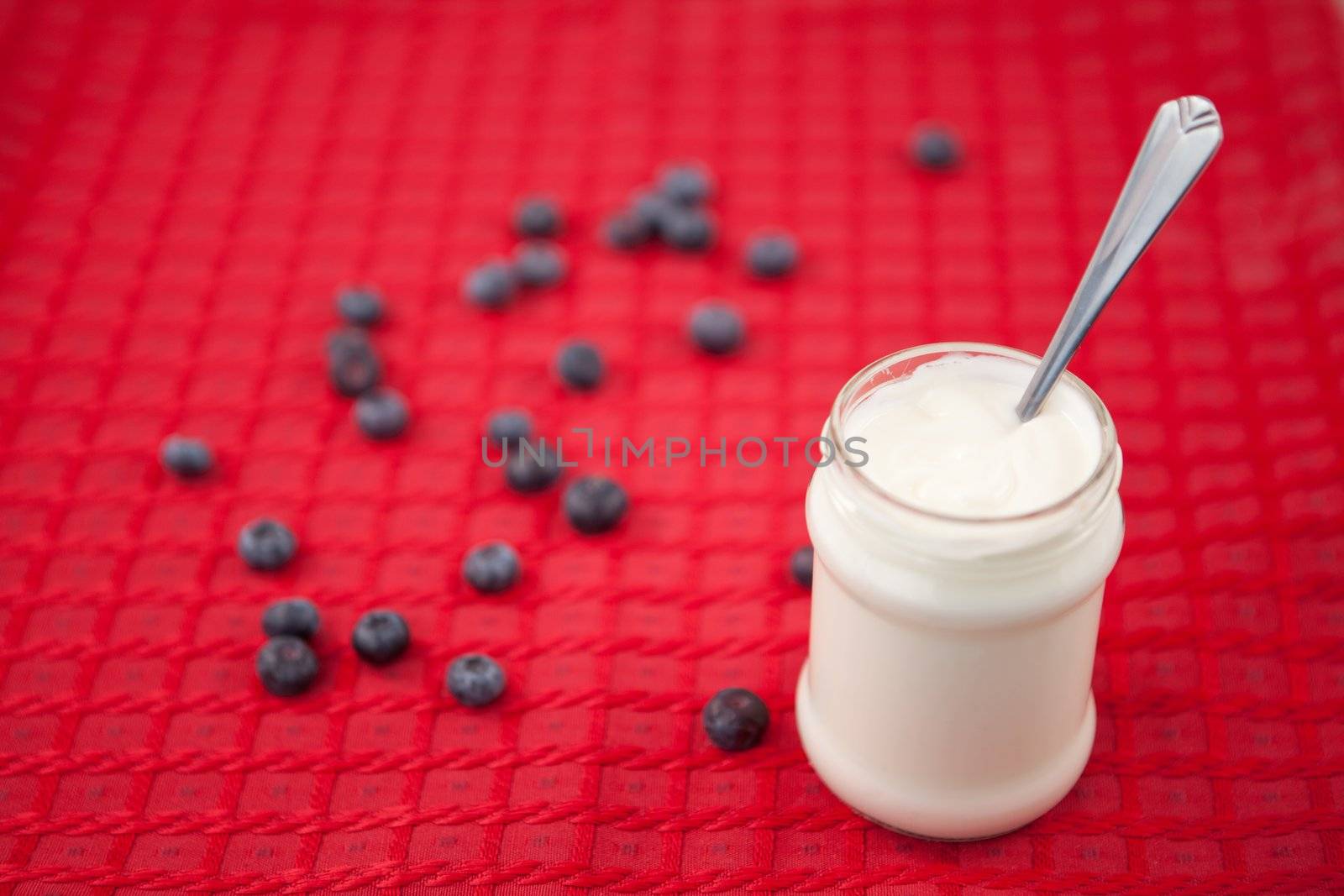 Pot of yoghurt and blueberries on a red tablecloth