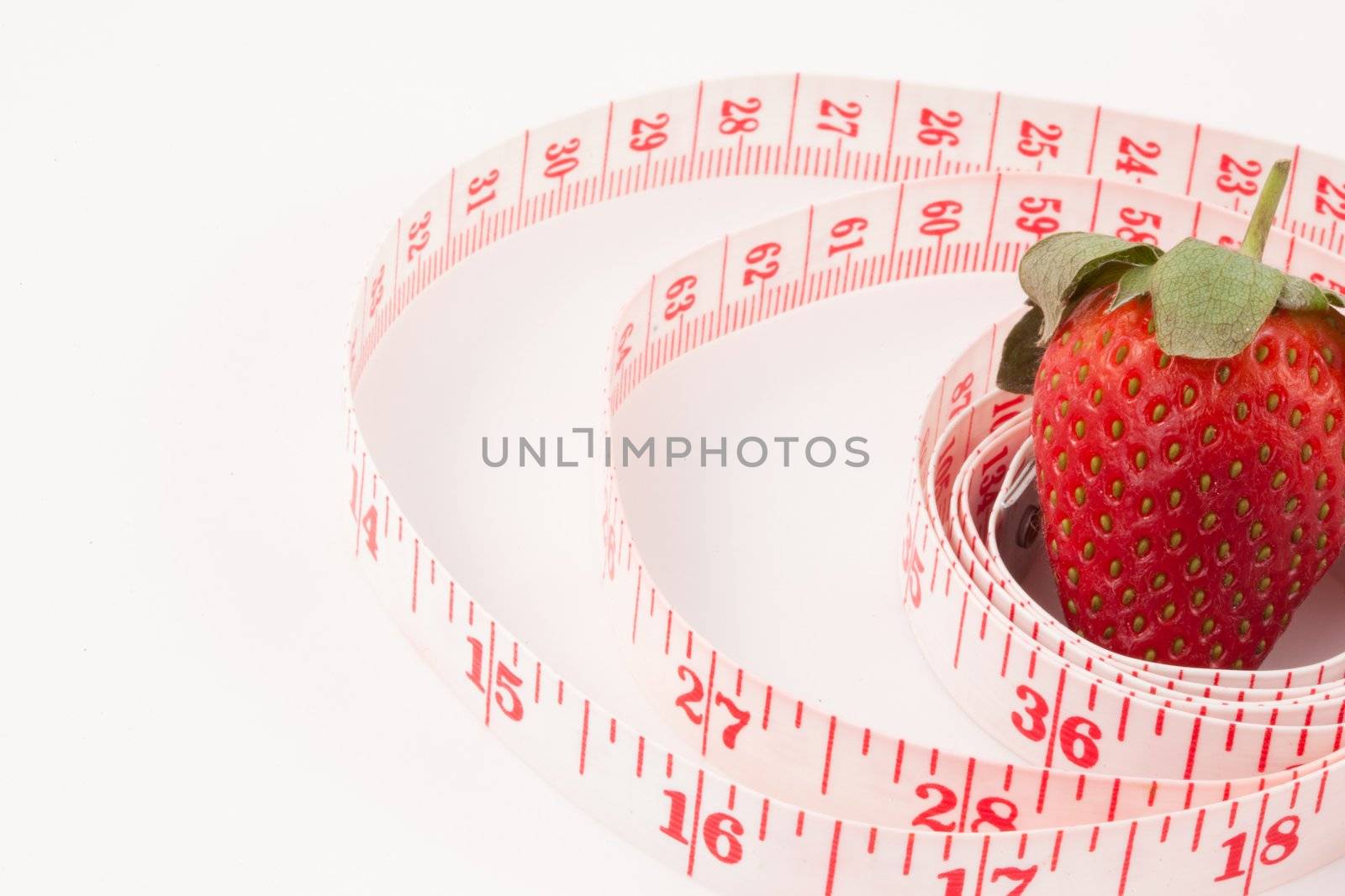Close up of a strawberry surrounded by a ruler against a white background