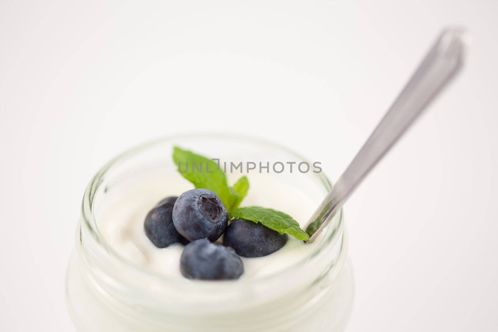 Close up of a pot of yoghurt with blueberries and fresh mint by Wavebreakmedia