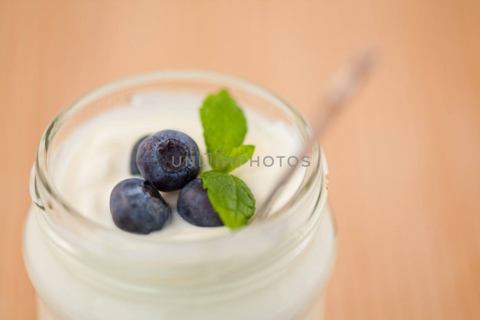 Close up of a pot of yoghurt with leaves and blueberries by Wavebreakmedia