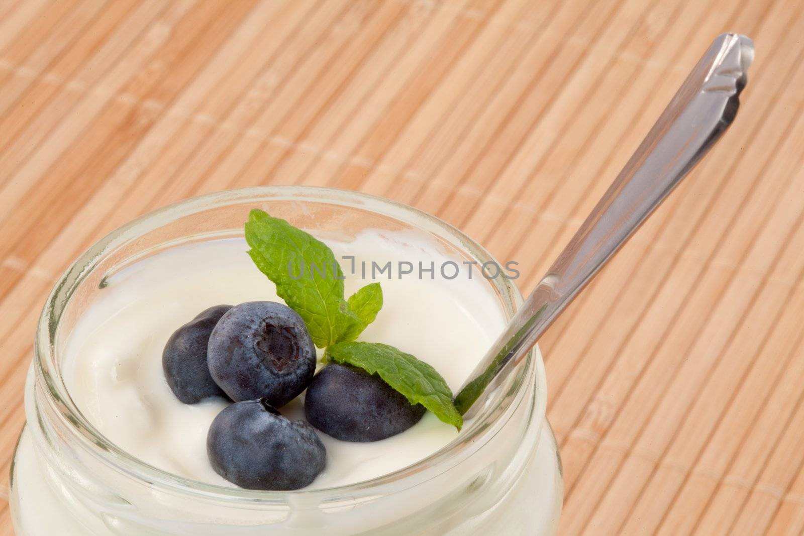 Close up of four blueberries in a yogurt by Wavebreakmedia