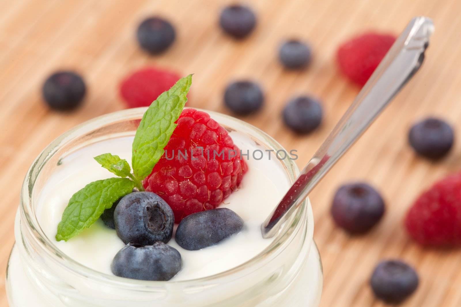 Close up of a pot yoghurt with mint blueberries and raspberry by Wavebreakmedia