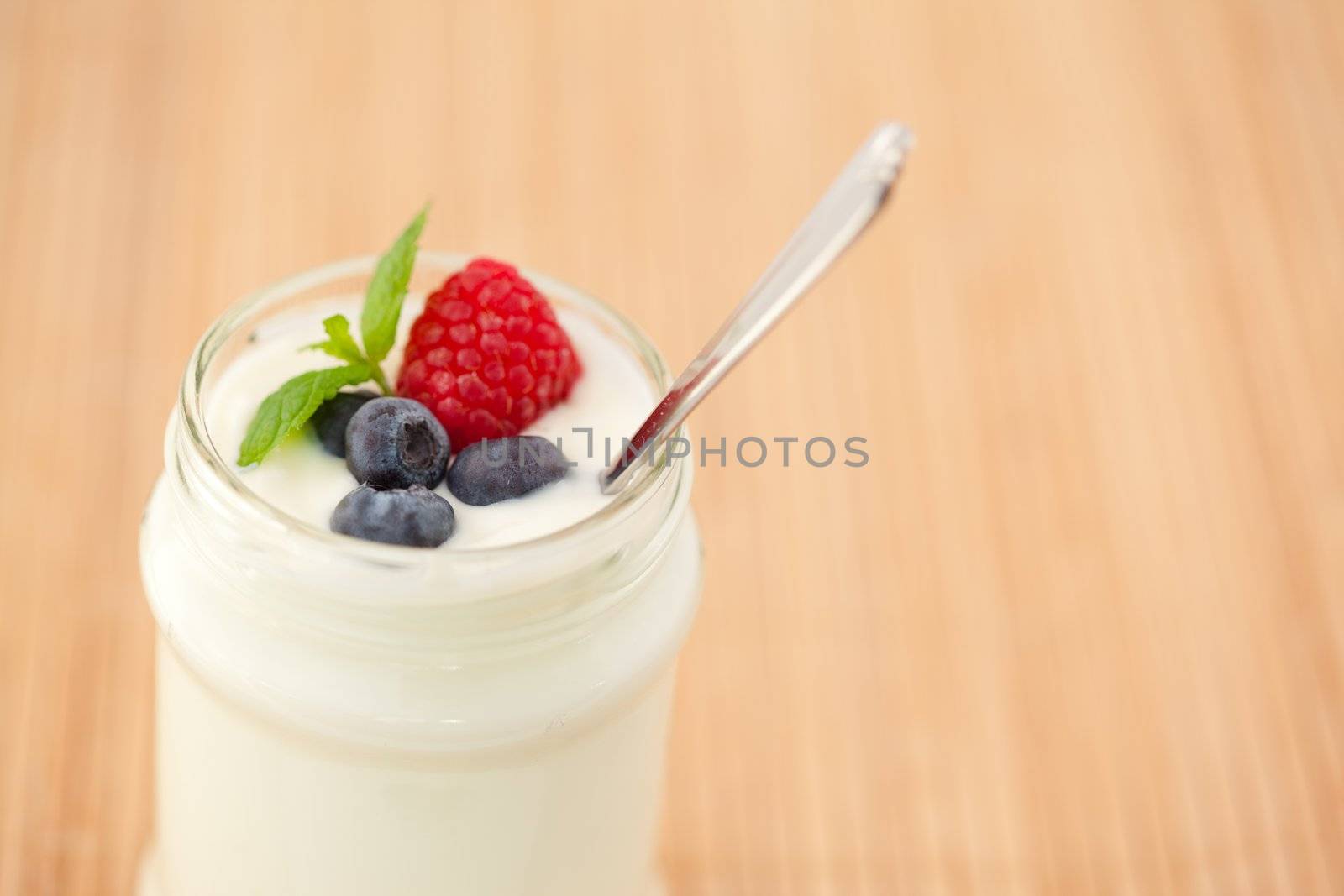 Close up of a pot yogurt with leaves red berries by Wavebreakmedia