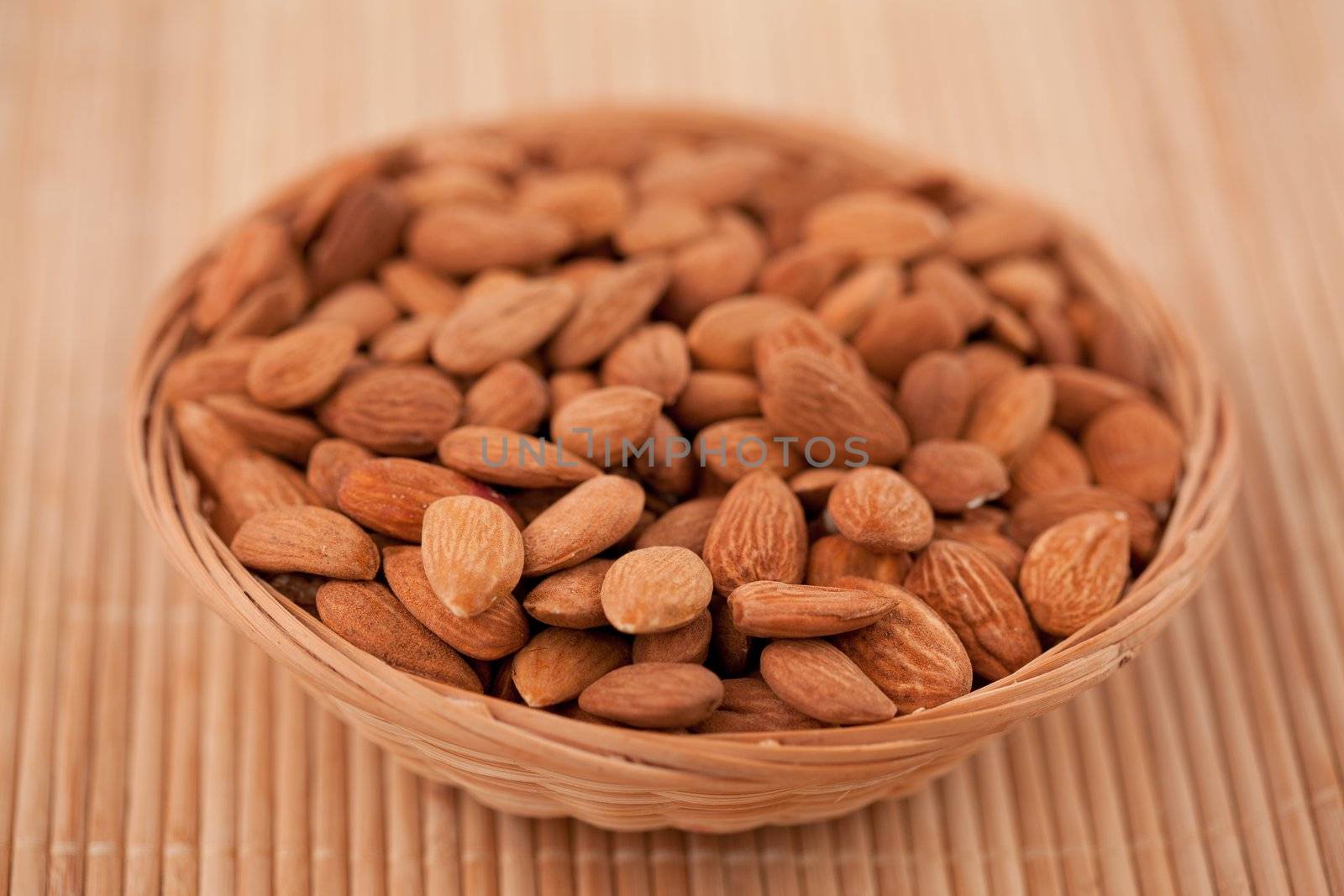Bowl full of roasted almonds on a wooden placemat