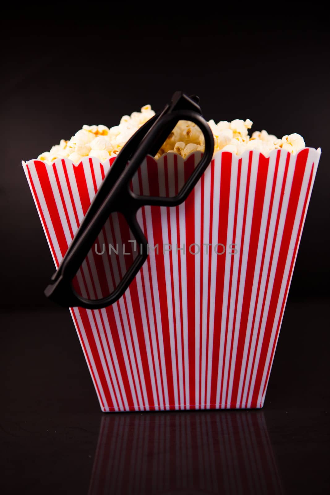 3D Glasses hanging on the edge of  a box full of pop corn by Wavebreakmedia