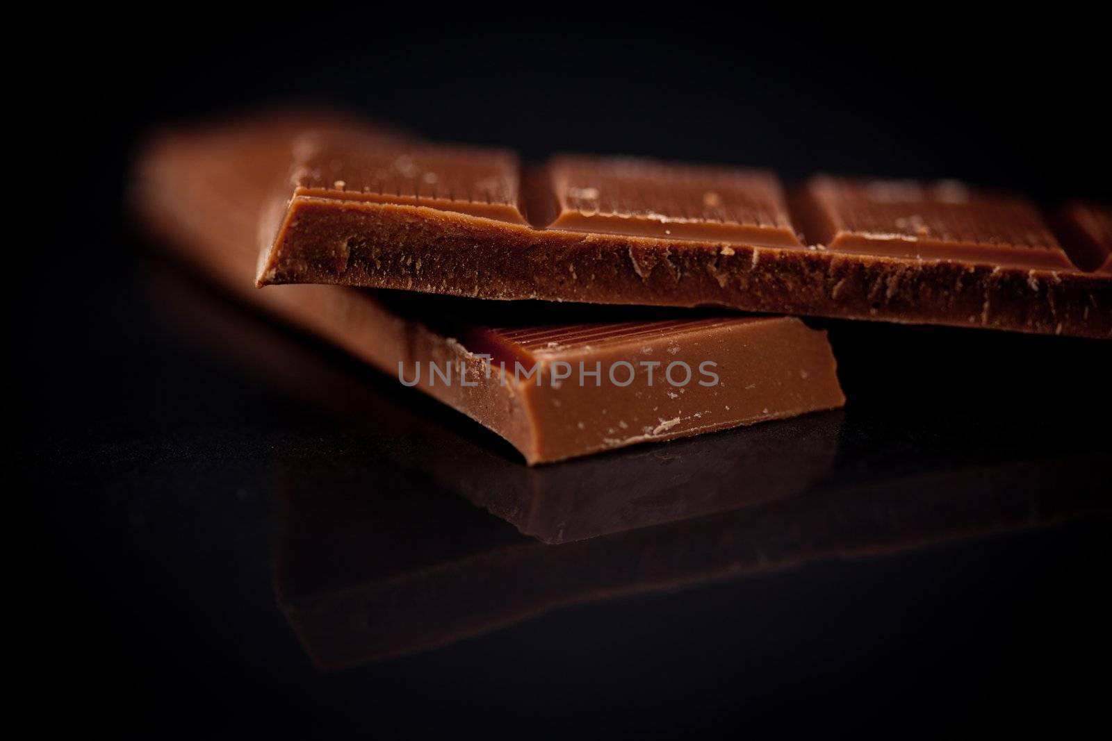 Two blurred bar of dark chocolate against a black background