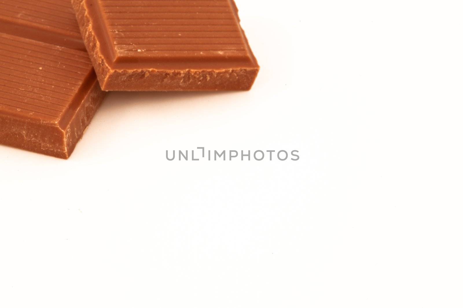 Two pieces of milk chocolate against a white background 