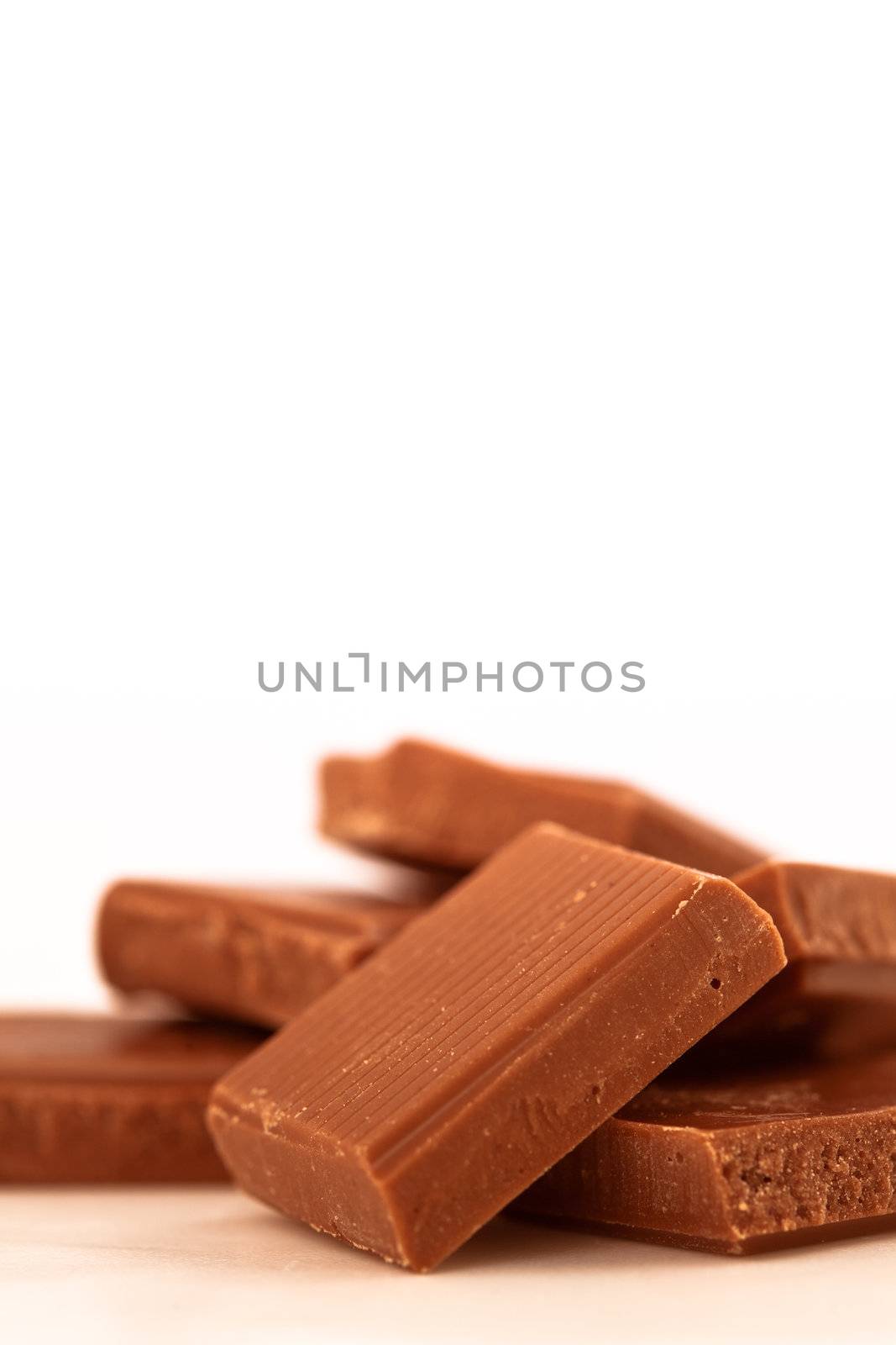 Many chocolate pieces piled together against a white background