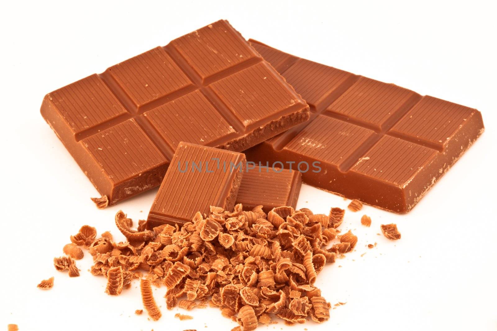 Bars of chocolate and chocolate shavings against a white background