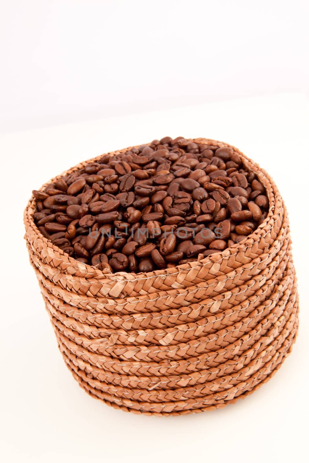 Close up of a basket full of coffee seeds against a white background