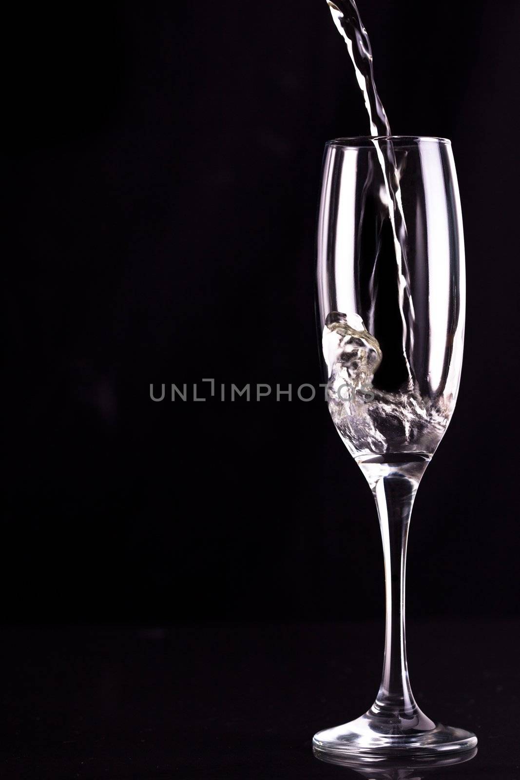 Empty champagne flute being filled against black background