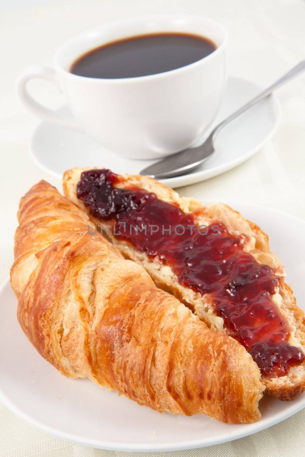 Coffee cup behind a croissant on a table