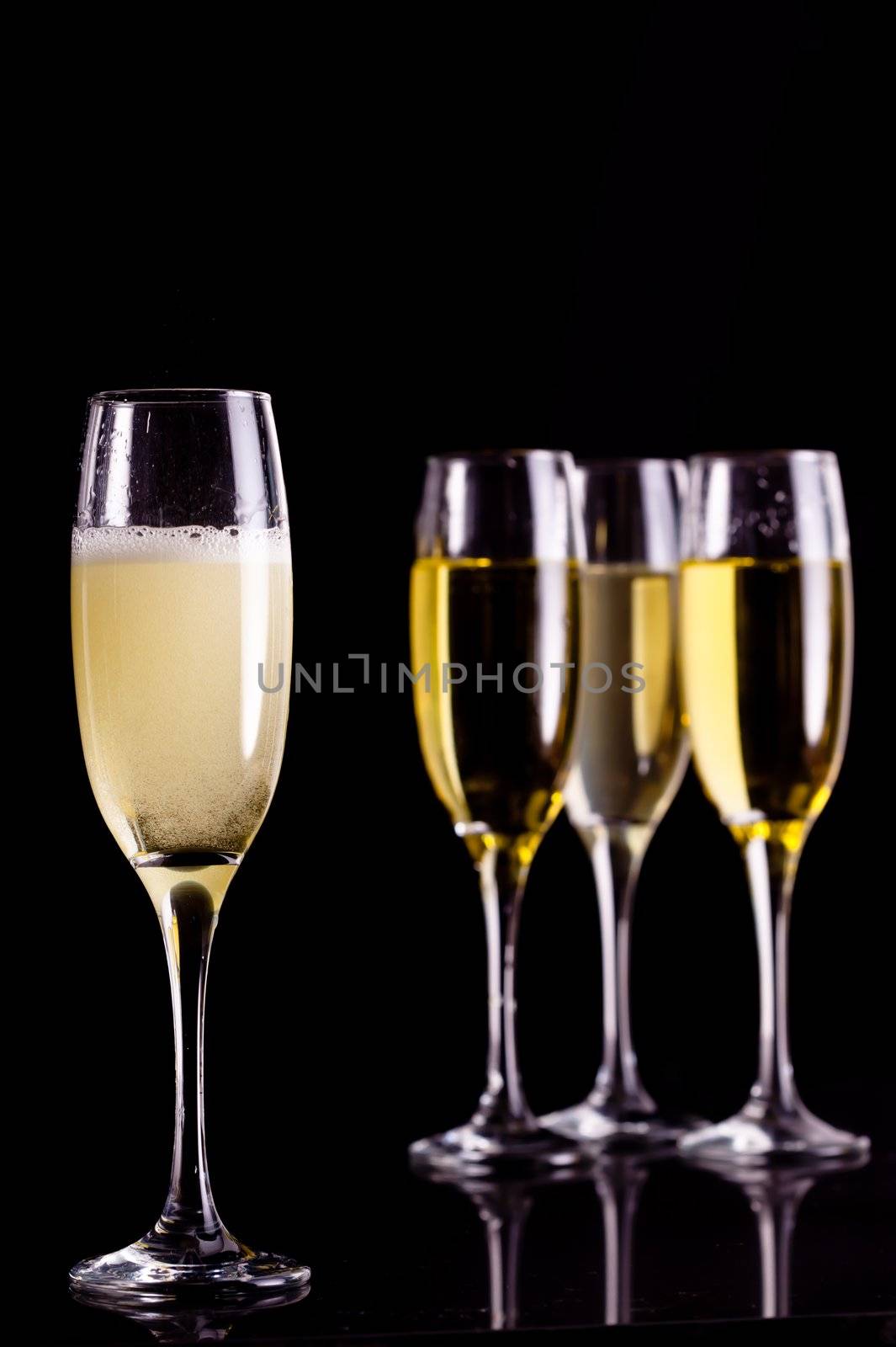 Four full flutes of champagne against black background