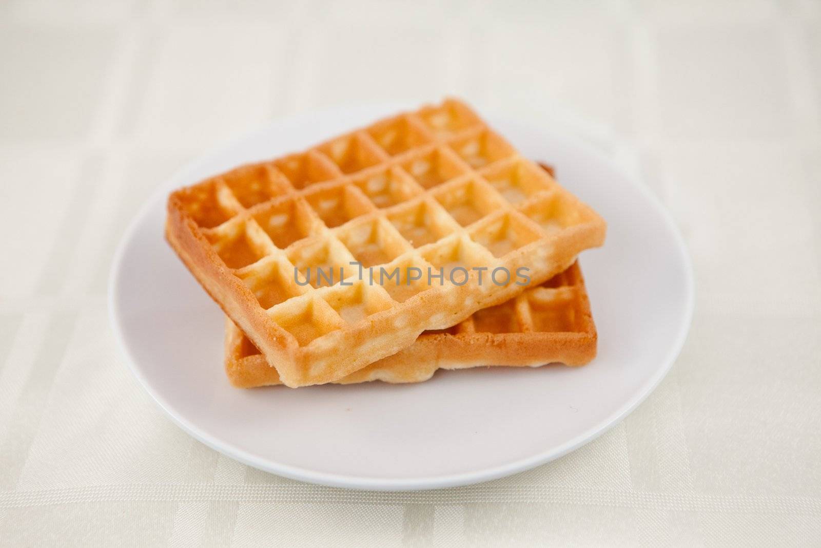 Two waffles on a saucer on a table