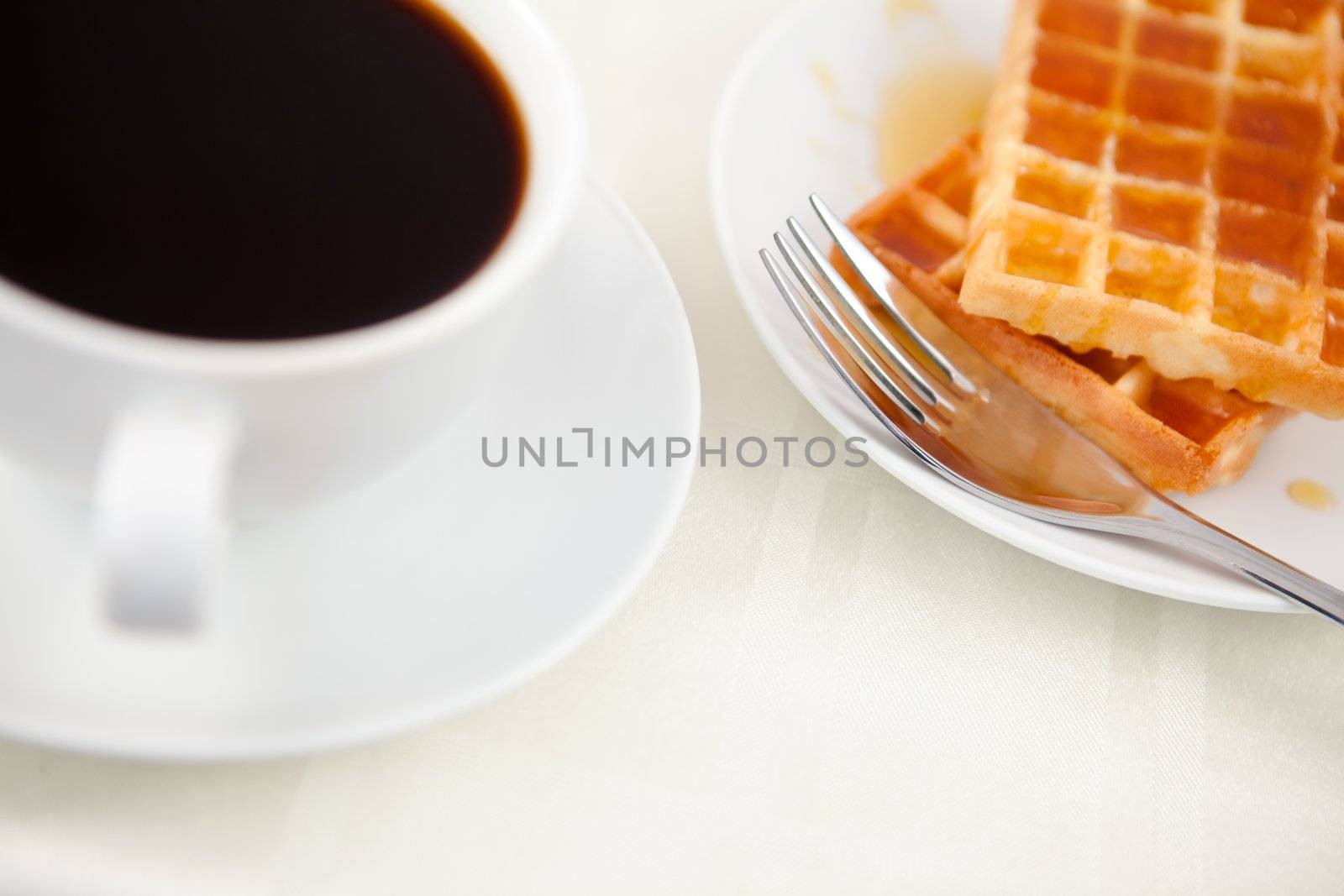 Waffles placed next to a coffee cup on a table