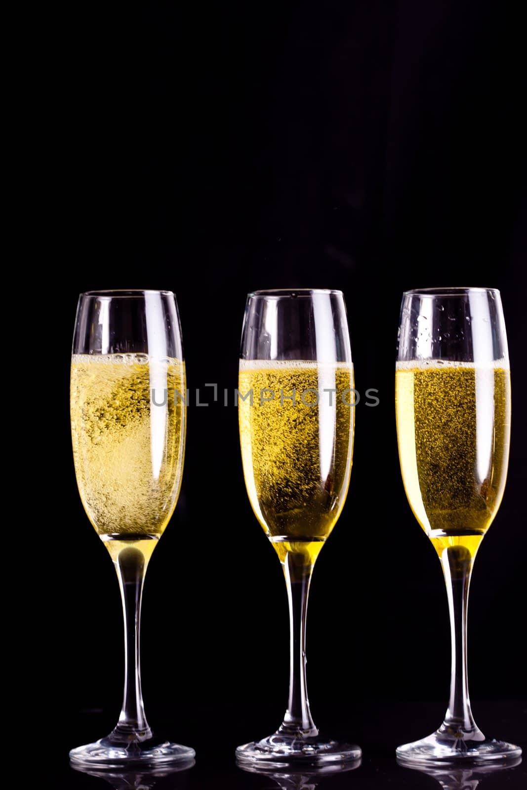 Three full glasses of champagne against black background