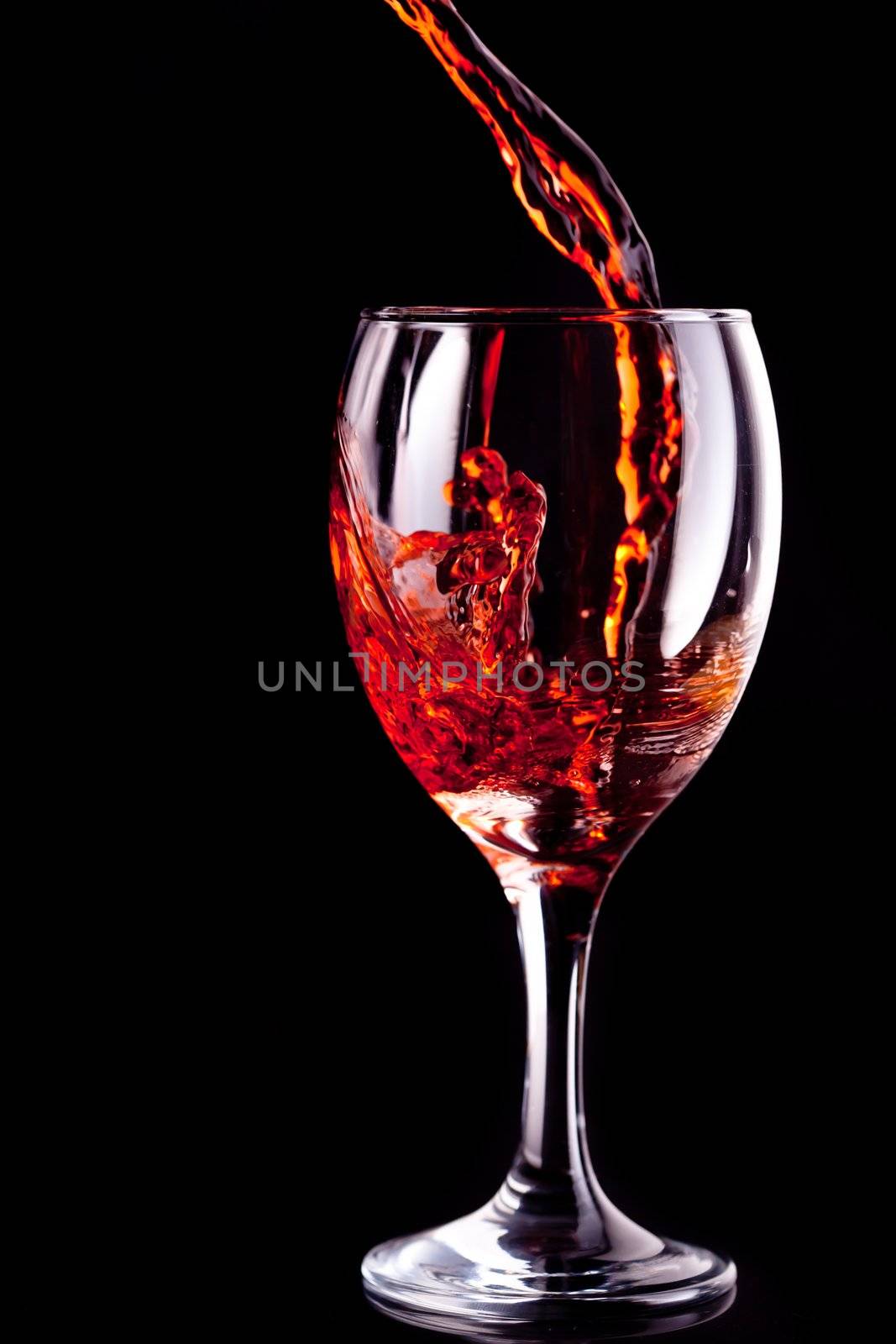 Empty glass being filled with wine against black background