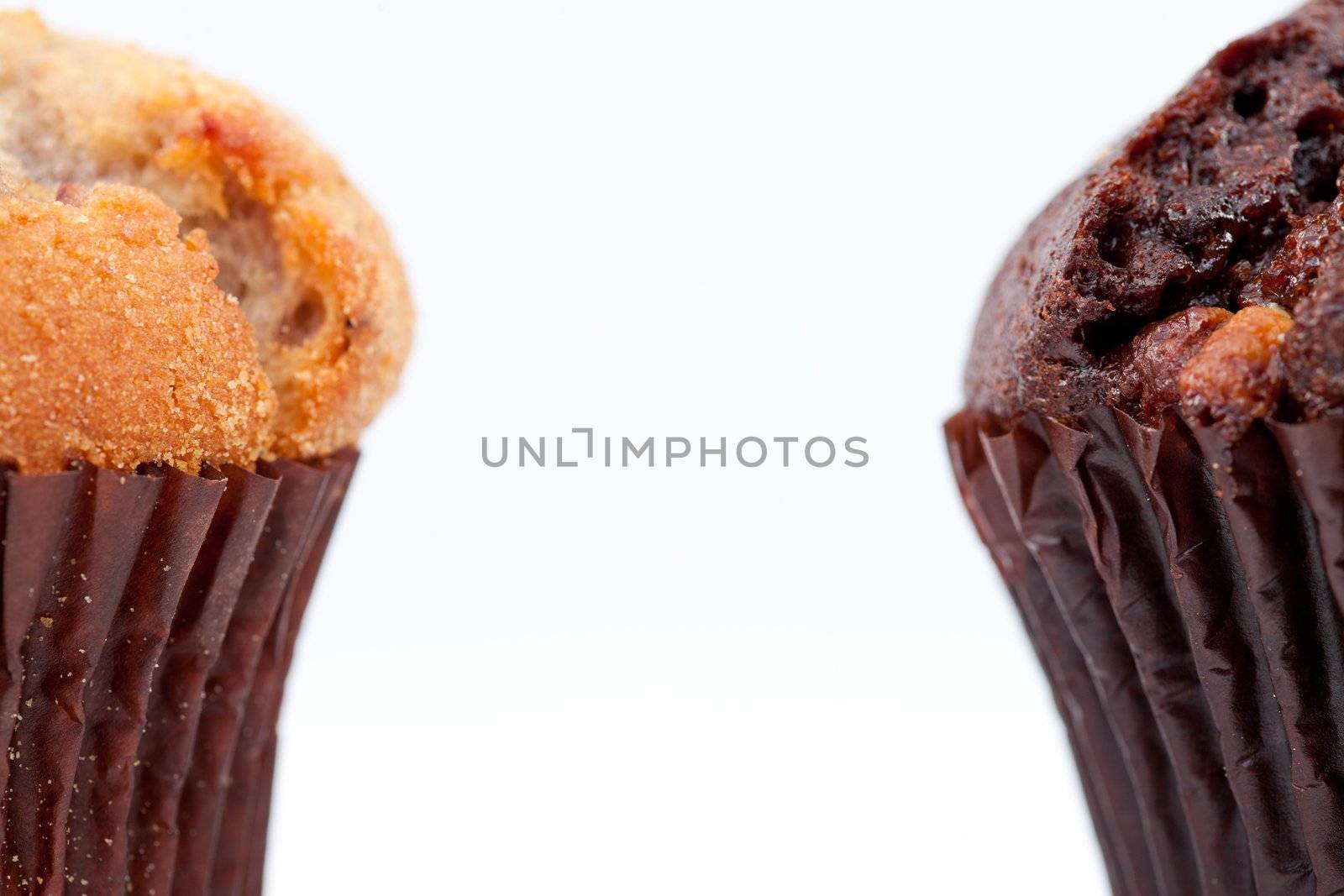 Close up of a chocolate muffin and a regular muffin against a white background