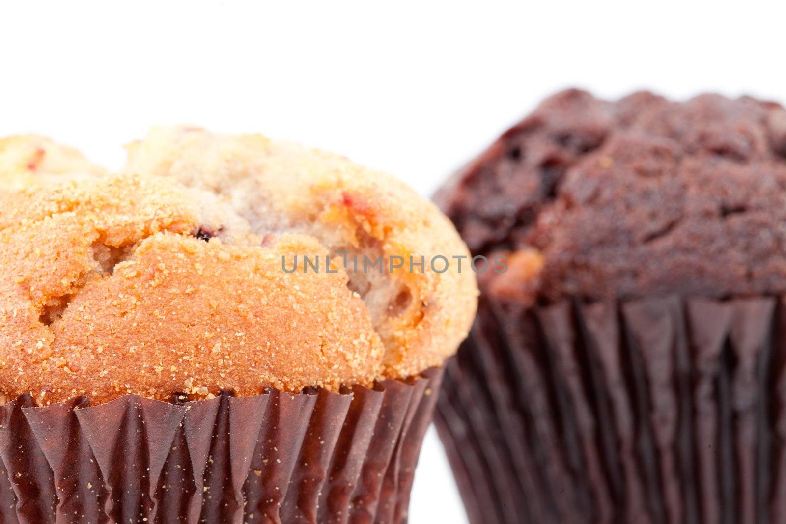 Close up of a regular muffin and a chocolate muffin against a white background