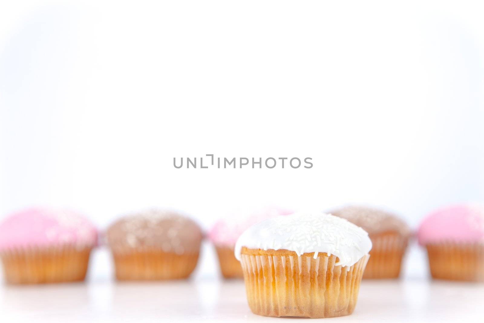 White muffin placed in front of a line of muffin with icing sugar against a blue background