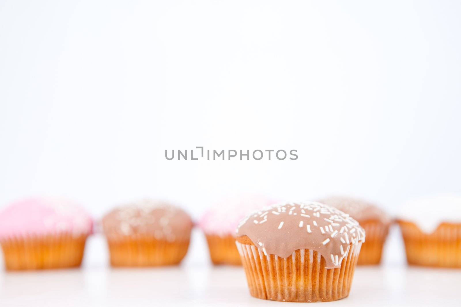 Muffins with icing sugar placed in line against a white background