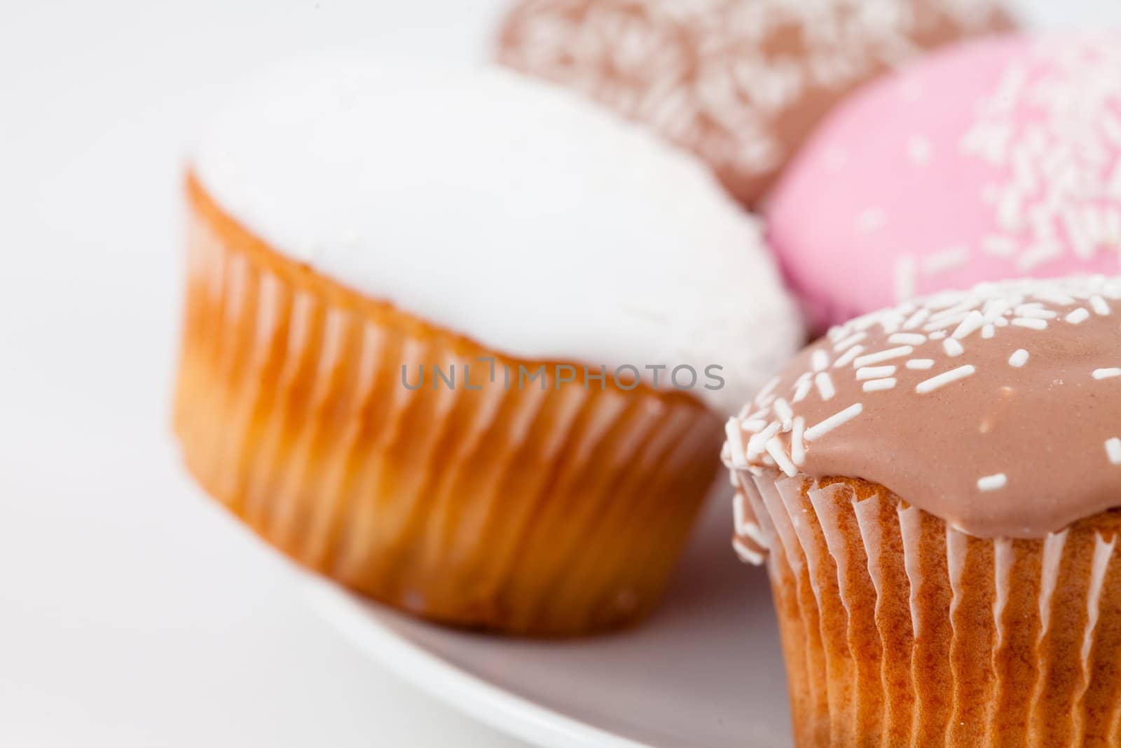 Close up muffins with icing sugar on a white plate against a white background