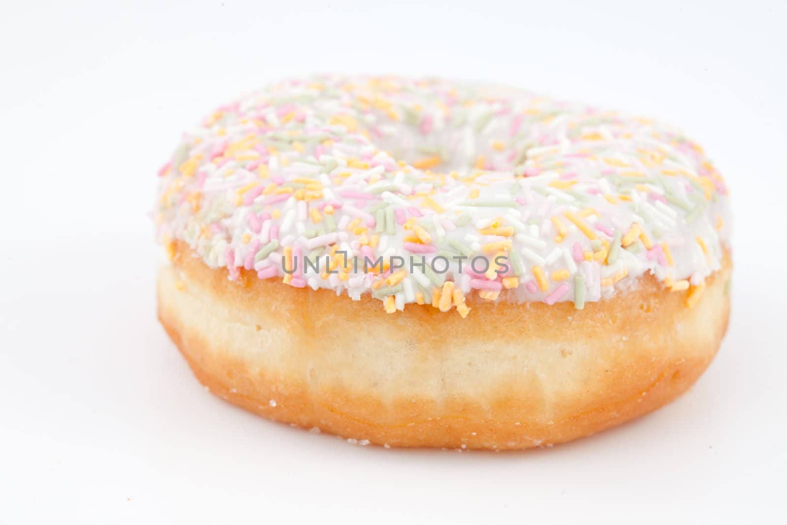 Close up of a doughnut with multi coloured icing sugar against a white background