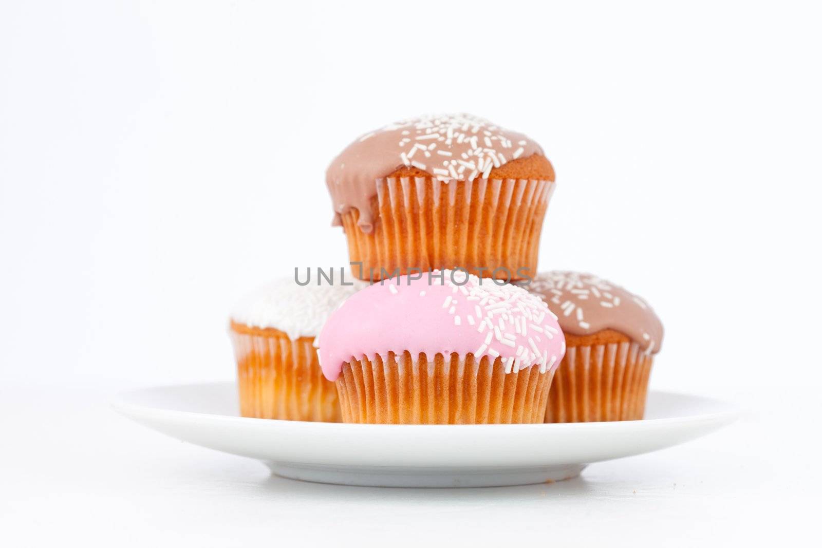 Muffins with icing sugar piles up on a white plate against a white background