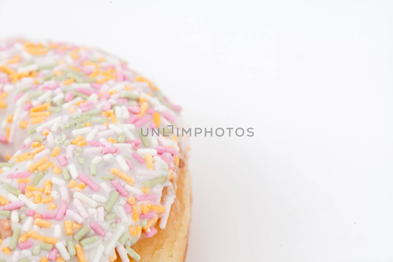 Close up of a doughnut with multi coloured icing sugar against a white background
