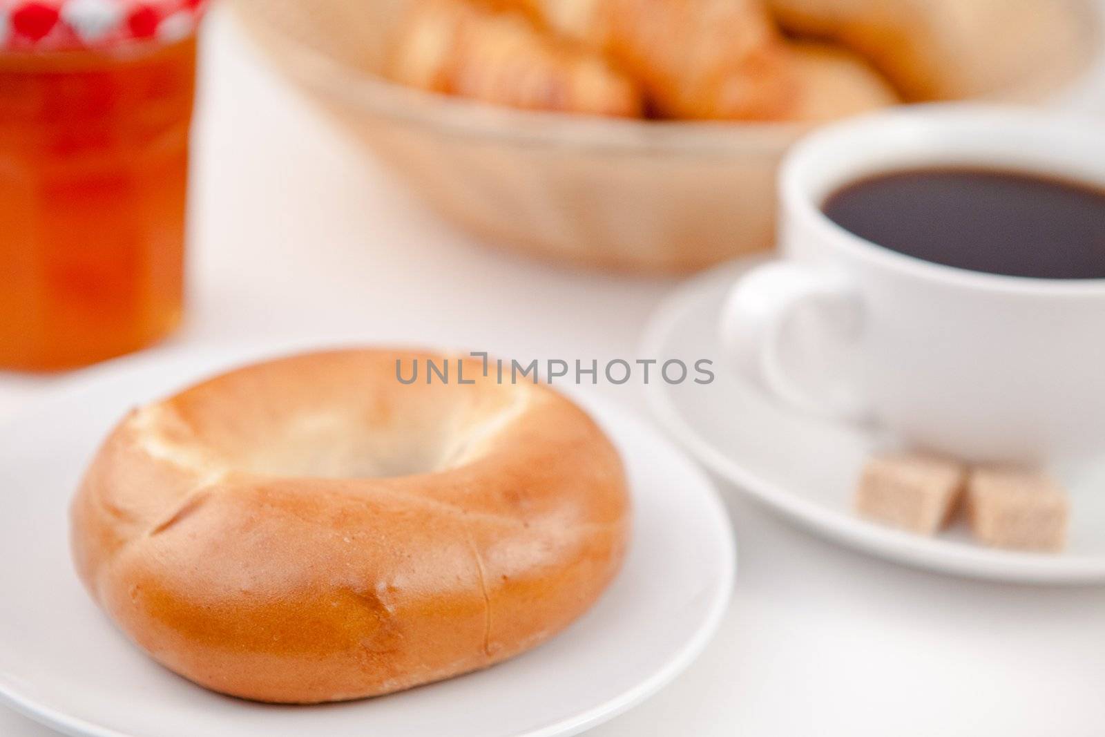 Doughnut and a cup of coffee on white plates with sugar and milk against a white background