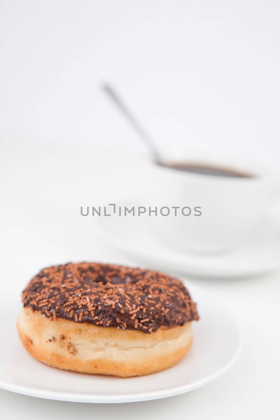 Chocolatedoughnut and a cup of coffee on white plates against a white background