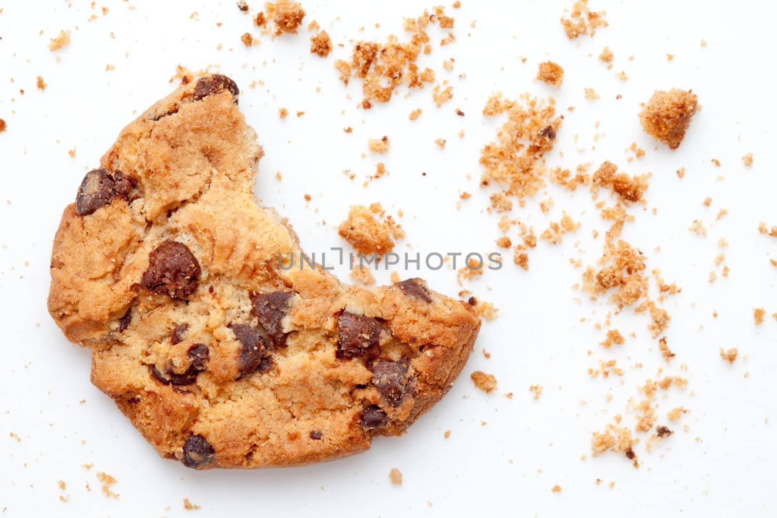 Close up of an half eaten cookie with crumb against a white background