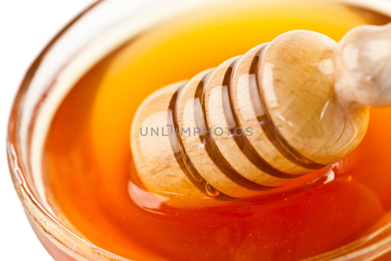 Honey dipper outgoing a bowl against a white background