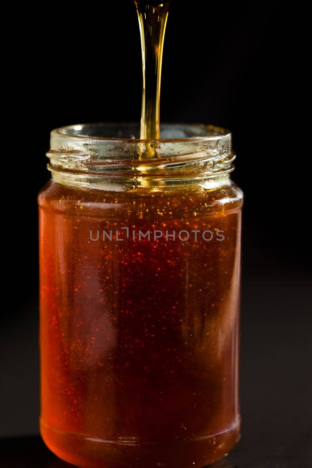 Honey trickle dropping in a honey jar by Wavebreakmedia