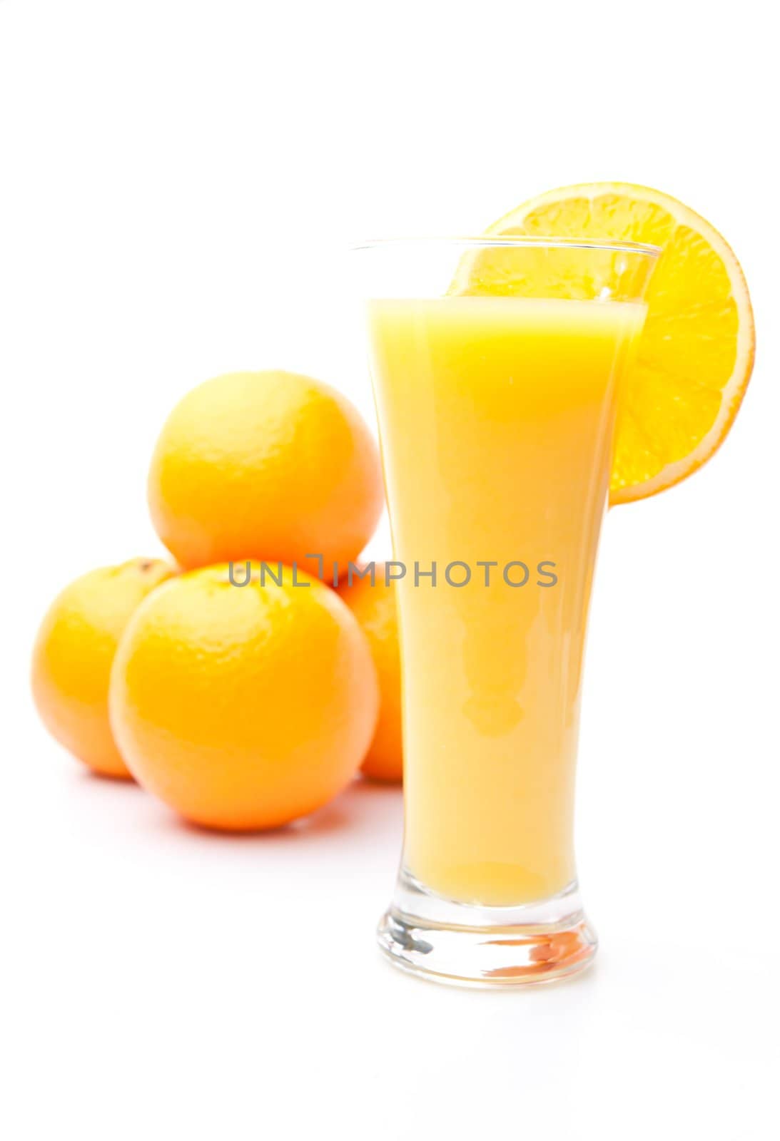 Pile of oranges behind a glass of orange juice by Wavebreakmedia