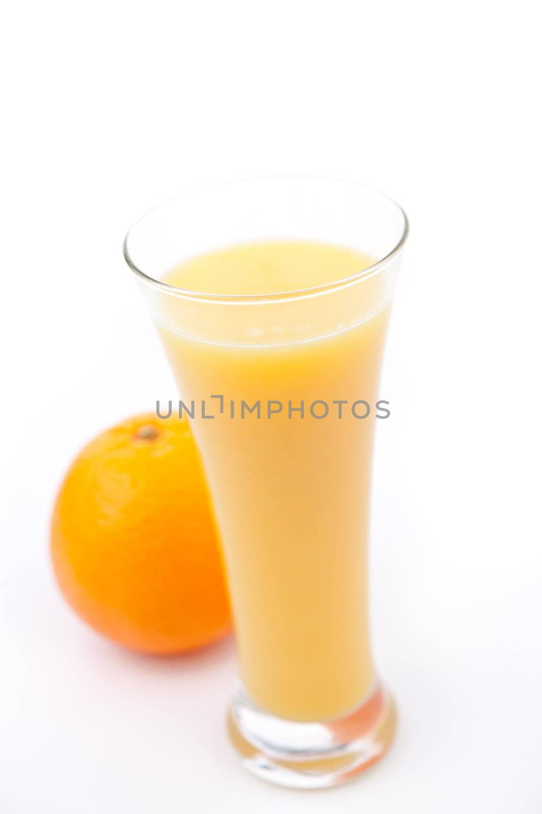 Orange behind a full glass of orange juice against white background