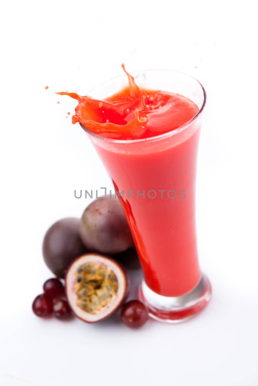 Overflowing glass of berries juice against white background