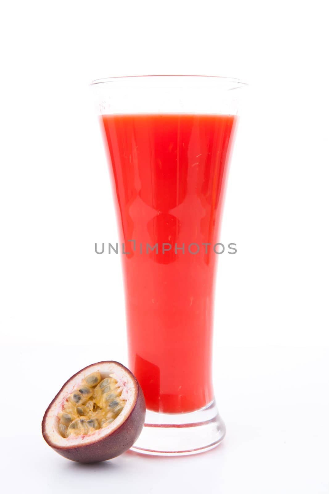 Full glass of berries juice near a passion fruit against white background