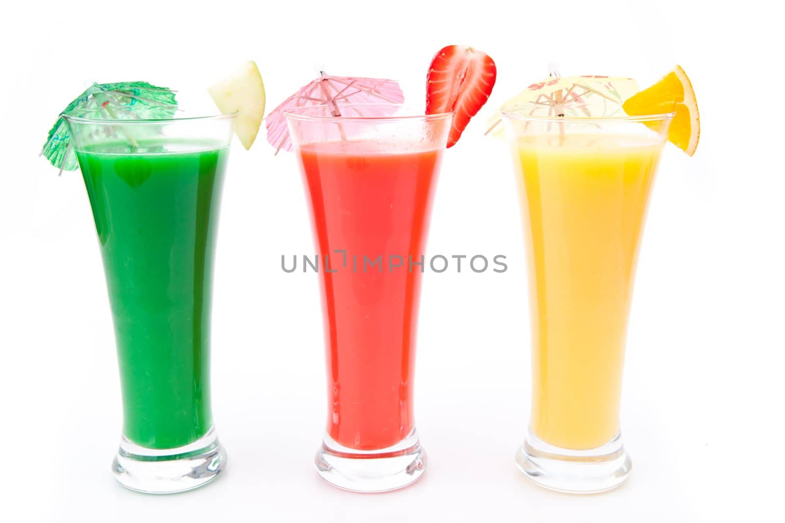 Fruit pieces and cocktail umbrella in a row of glasses against white background
