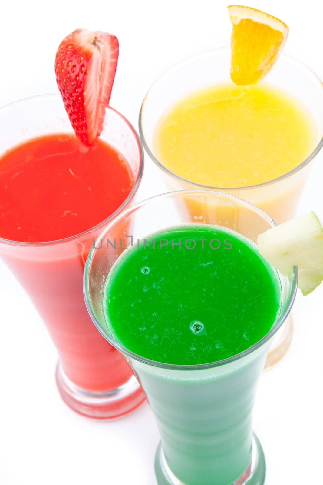 Fruits pieces placed on full glasses against white background