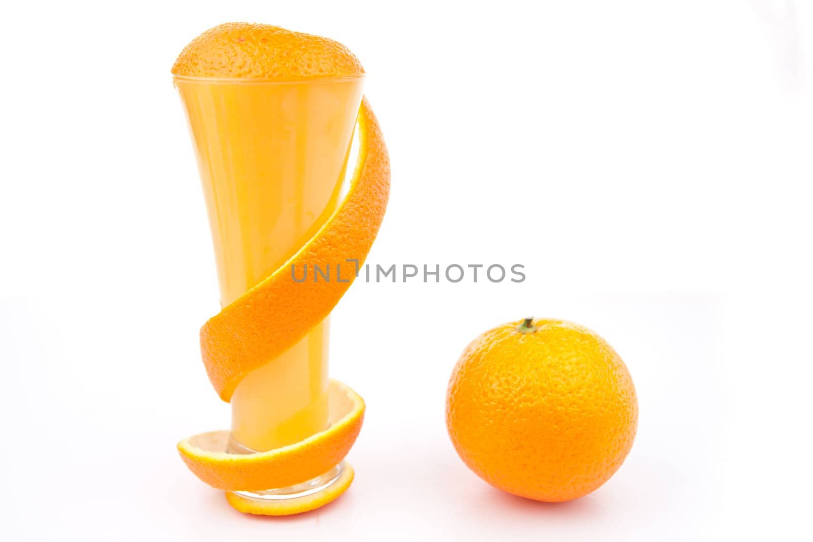 Orange peel surrounding a glass against white background