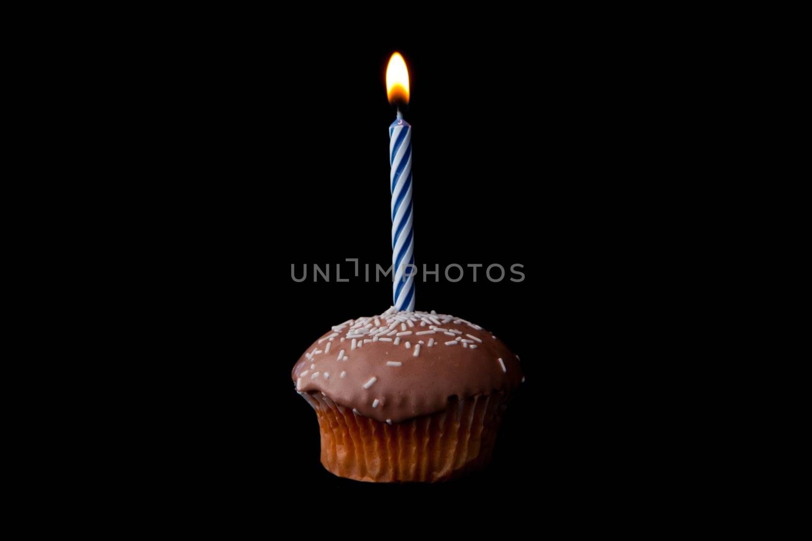 Brown cake with candle against a black background