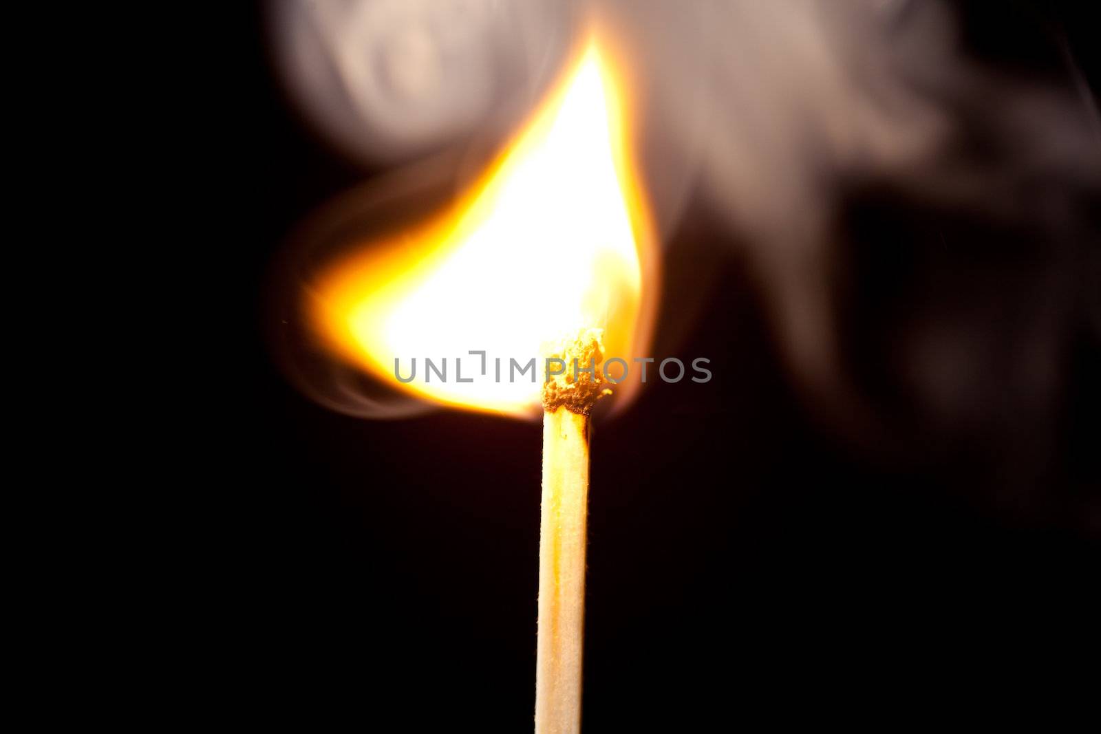 Match set on fire against a black background