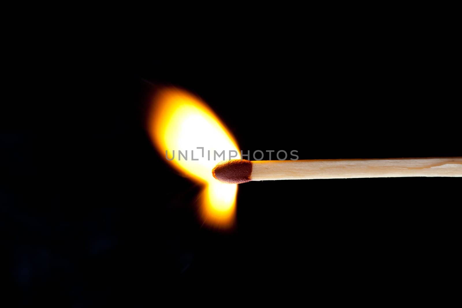 Horizontal match set on fire against a black background