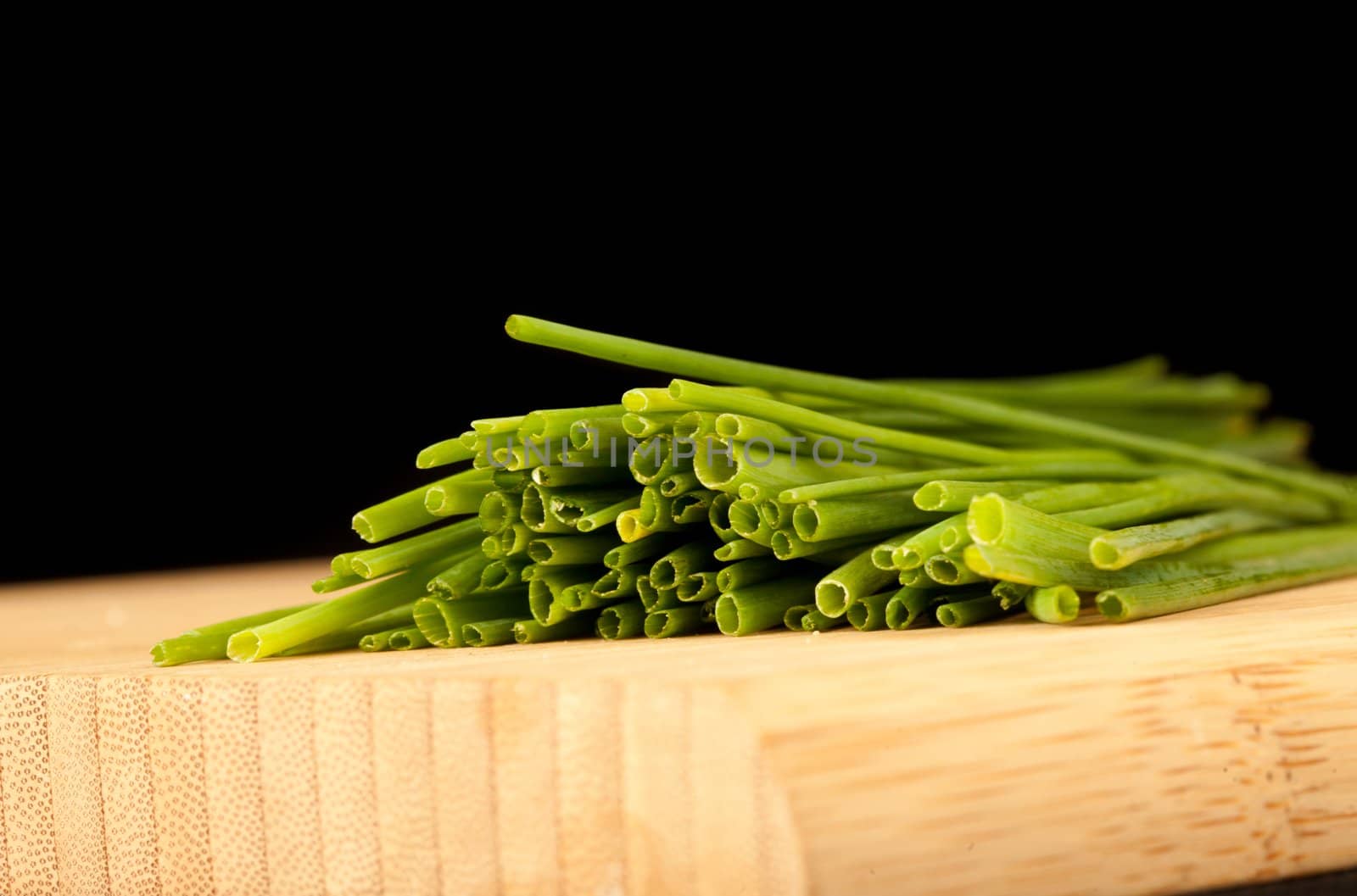 Stands of chive against a black background