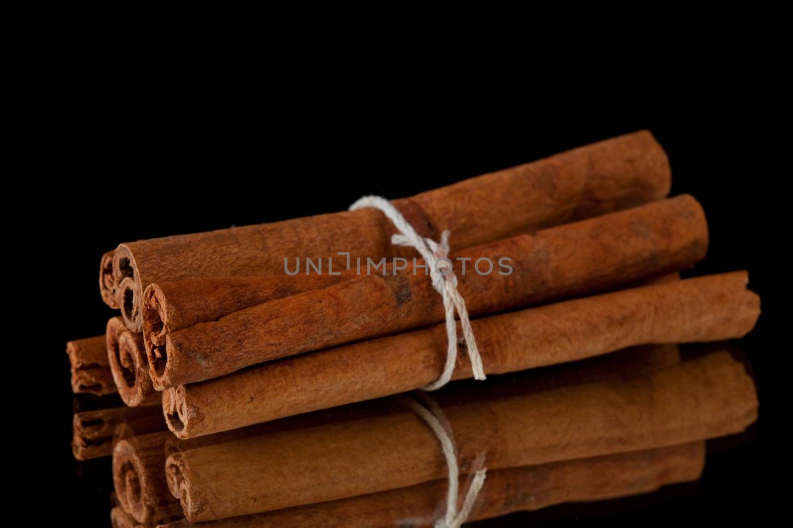 Cinnamon sticks packed together against a black background