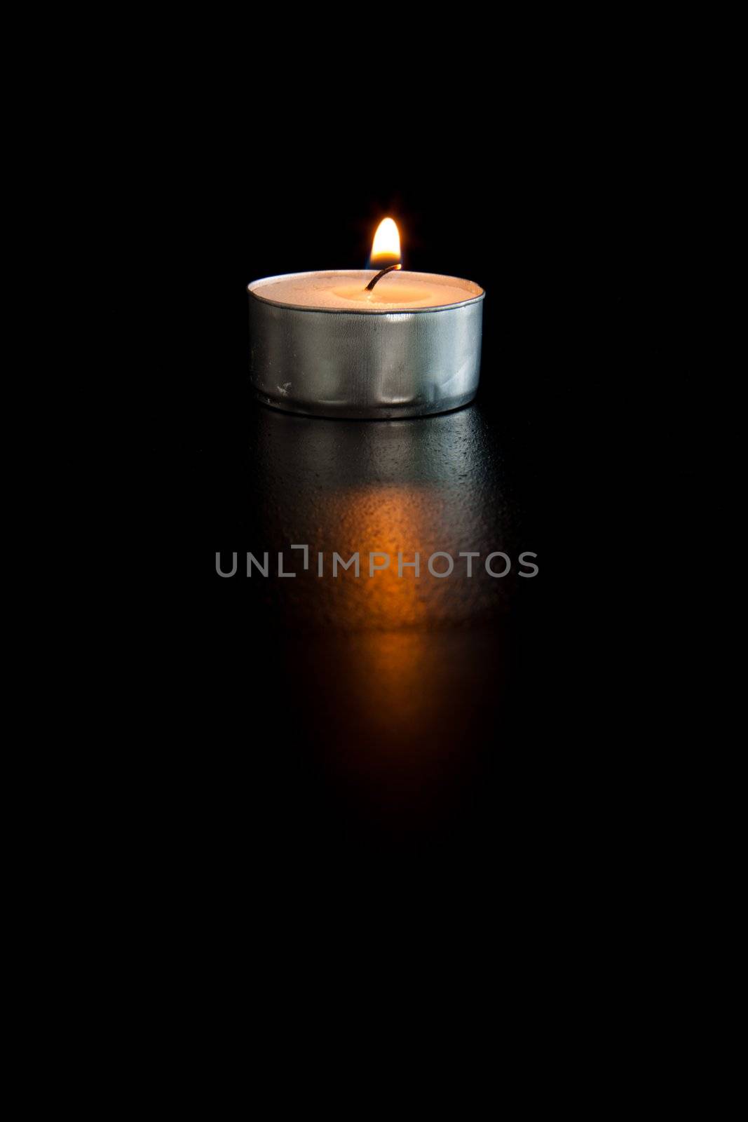 Lightened tea candle against a black background