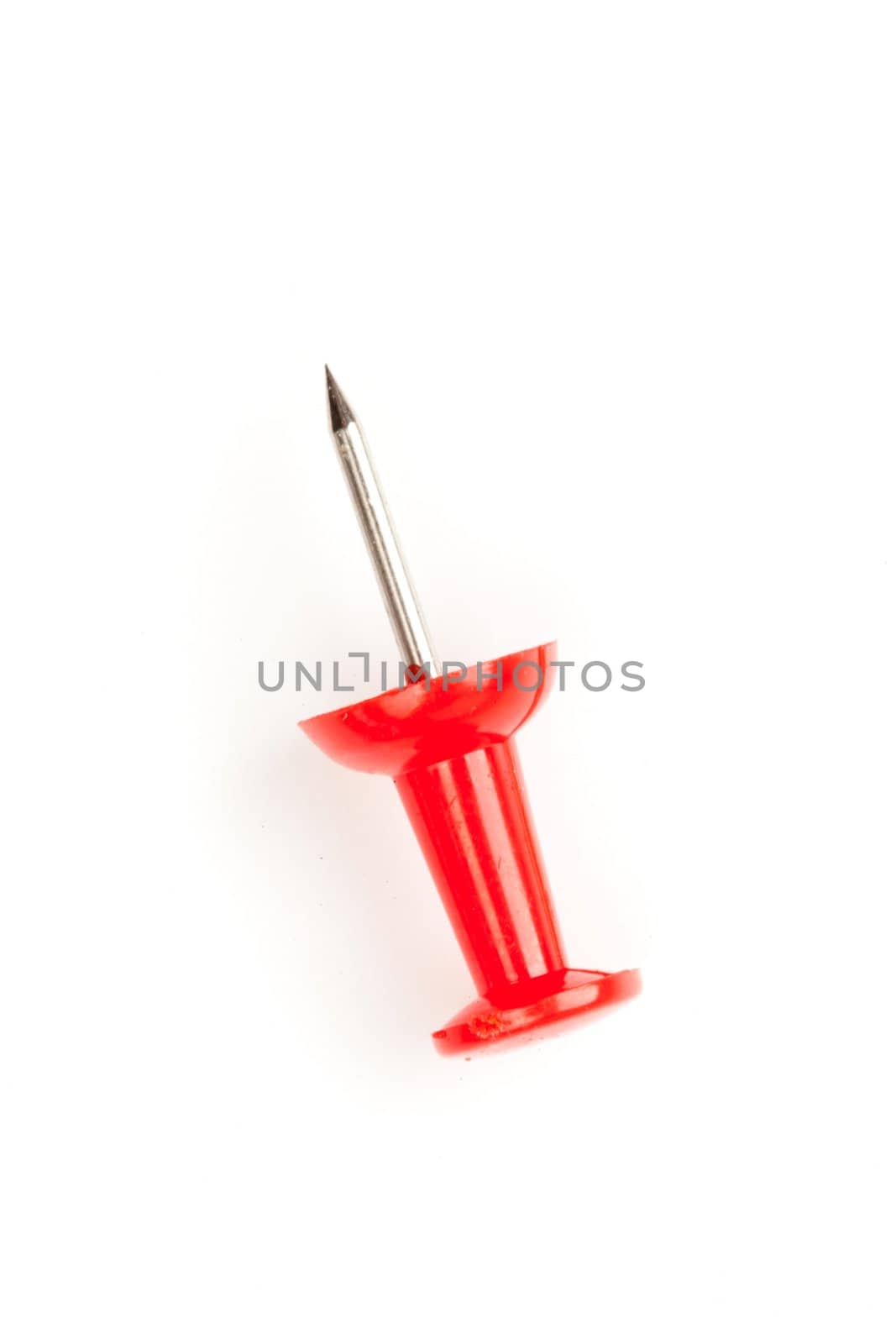 Close up of a red pushpin on the floor against a white background