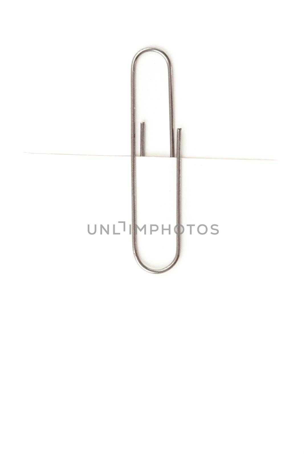 Close up of a grey paperclip attaching on a white paper against a white background