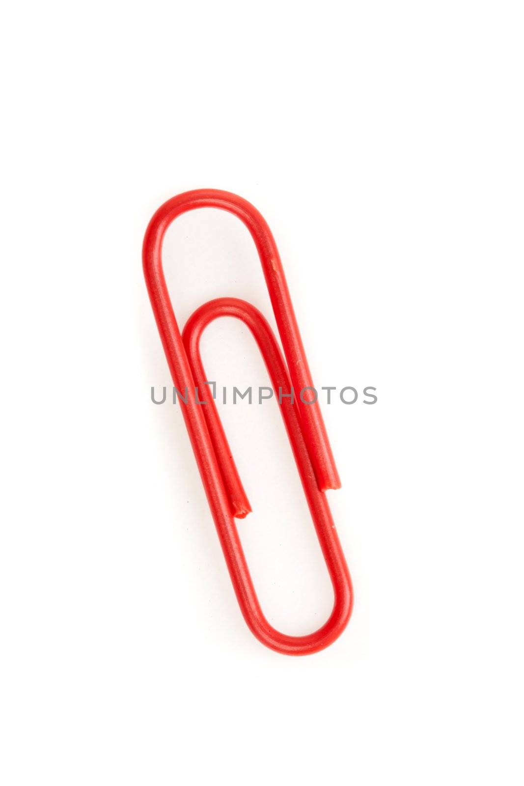 Close up of a red paperclip on the floor against a white background